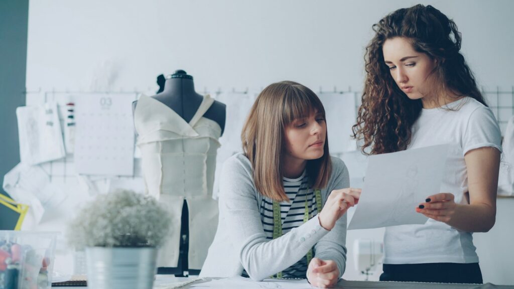 Modedesigner besprechen Entwürfe im Atelier, typische Teamarbeit hinter neuen Kollektionen