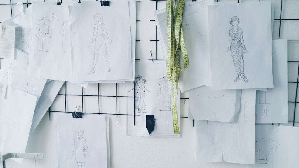Modeskizzen an einer Gittertafel, wie sie deutsche Designerinnen bei der Entwurfsarbeit nutzen