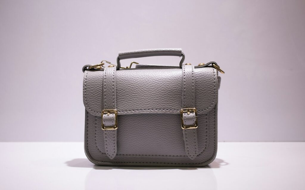 Graue Ledertasche mit goldenen Schnallen