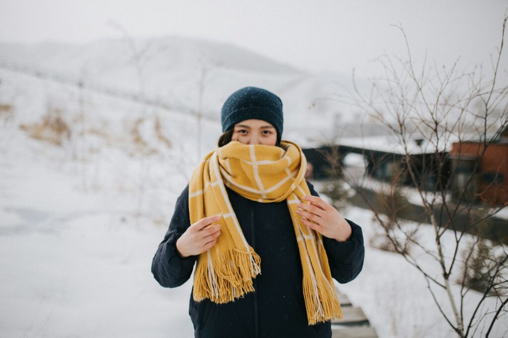 Frau mit Strickmütze und Jacke im Schnee zeigt Layering im Winter