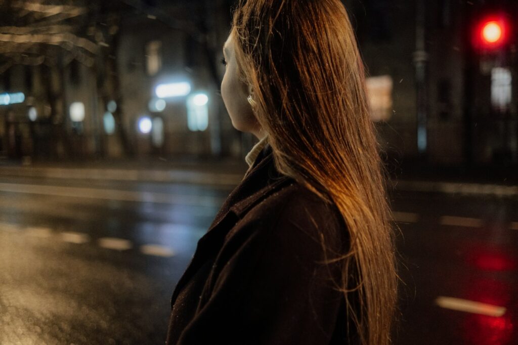 Frau im Oversize-Mantel auf einer nächtlichen Straße