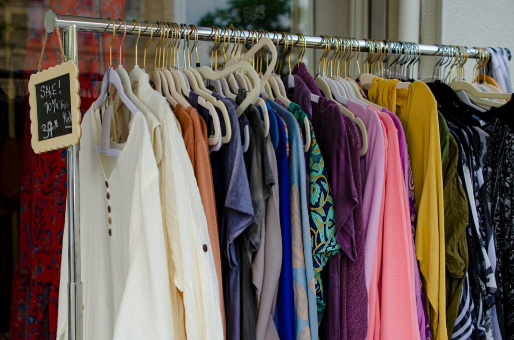 Gebrauchte Kleidung auf Bügeln an einer Kleiderstange, ideal für alle, die Second Hand online kaufen