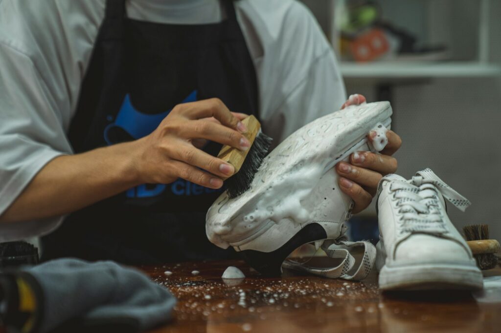 Sneaker reinigen: Person hält ein Paar Schuhe an einem Tisch