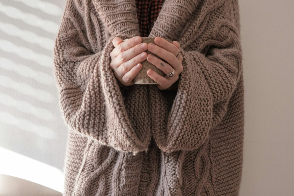 Person im braunen Strickpullover als Inspiration zum Strickjacke kombinieren