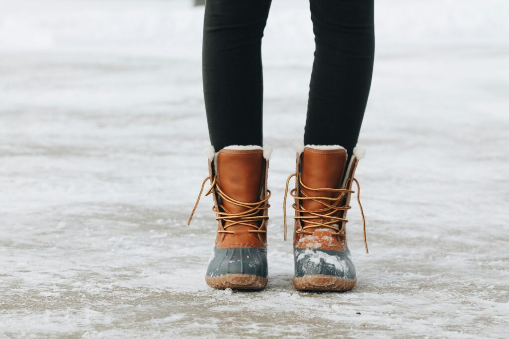 Person in Winterstiefeln auf dem Waldboden
